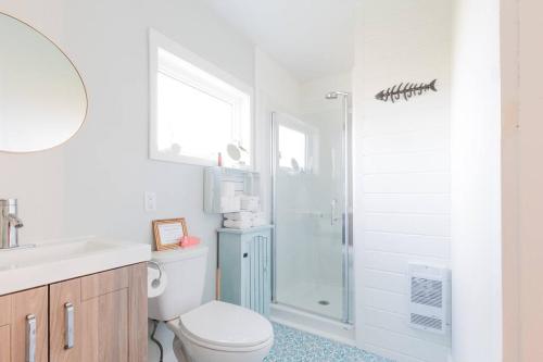a white bathroom with a toilet and a shower at Seahorse Cottage in Indian Harbour