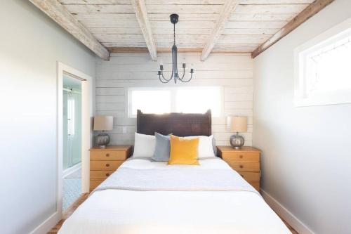 a bedroom with a large white bed with a chandelier at Seahorse Cottage in Indian Harbour