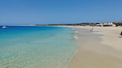 a beach with people walking on the sand and the water at Albis Harena - Meridiana Private Apartment Ocean View in Santa Maria