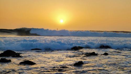 a sunset over the ocean with waves and the sun setting at Albis Harena - Meridiana Private Apartment Ocean View in Santa Maria