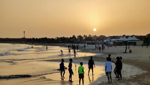 a group of people playing on the beach at sunset at Albis Harena - Meridiana Private Apartment Ocean View in Santa Maria