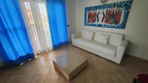 a living room with a white couch and blue curtains at Albis Harena - Meridiana Private Apartment Ocean View in Santa Maria
