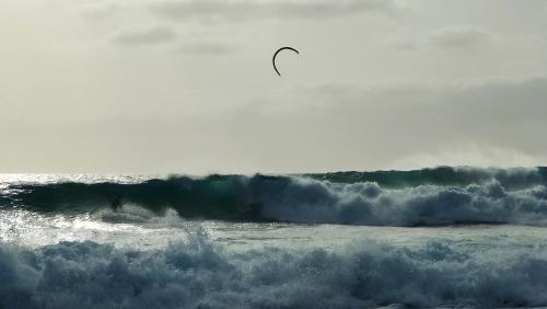 a person riding a wave in the ocean with a kite at Albis Harena - Meridiana Private Apartment Ocean View in Santa Maria
