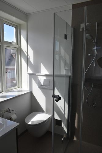 a bathroom with a toilet and a glass shower at Videbæk Hotel in Videbæk