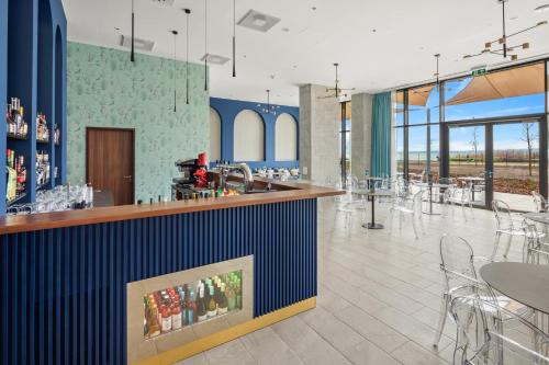 a restaurant with a bar and tables and chairs at Sirius Hotel****Superior in Keszthely