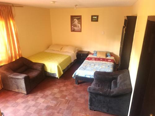 a bedroom with a bed and a couch and a chair at Hostal Globo in Quito