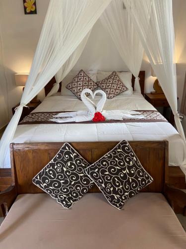 a bed with white sheets and pillows on it at D'JERO HomeStay in Ubud