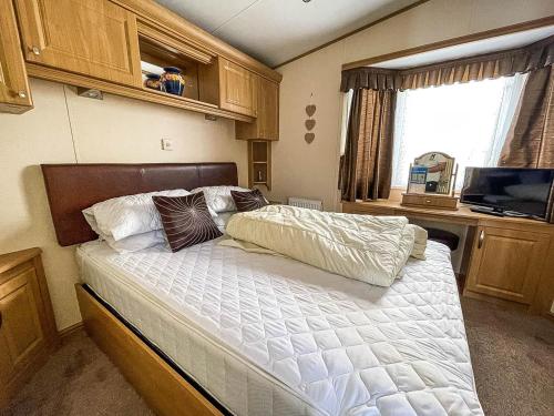 1 dormitorio con 1 cama, TV y ventana en Lovely Caravan With Large Decking At Naze Marine Holiday Park Ref 17306br, en Walton-on-the-Naze
