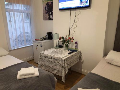 a room with two beds and a table with a tv on the wall at Double Room Central Location 2 in Plumstead