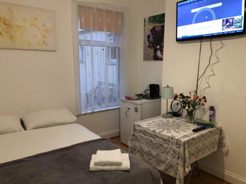 a bedroom with a table and a tv on the wall at Double Room Central Location 2 in Plumstead