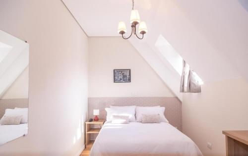 a white bedroom with a bed and a staircase at Village de Charme - 2km do Capivari in Campos do Jordão