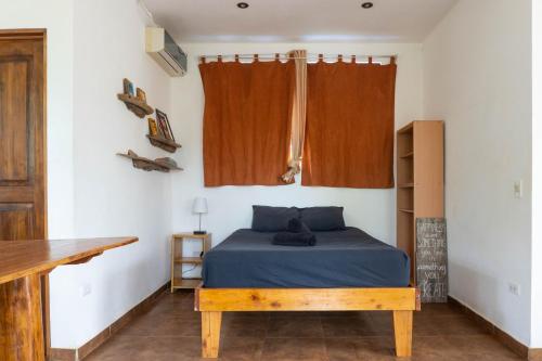 a bedroom with a bed and a wooden table at Mundaka : Burnt Toast Surfcamp in Nosara