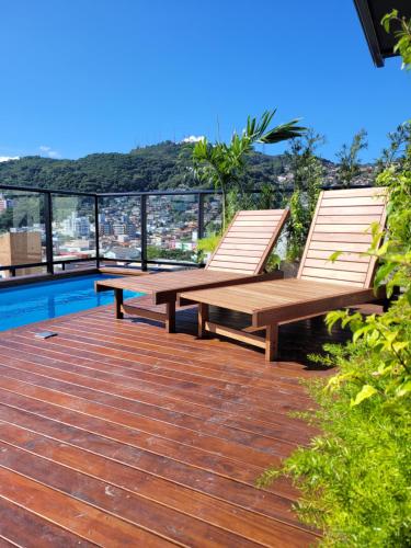 two wooden chairs sitting on a deck next to a pool at Bewiki in Florianópolis