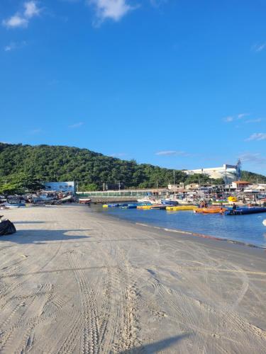 a sandy beach with boats in the water at Flat dos Anjos in Arraial do Cabo