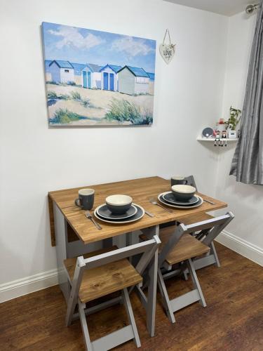 a dining room table with chairs and a painting on the wall at Cottage, 10 mins Train / River in Burnham on Crouch