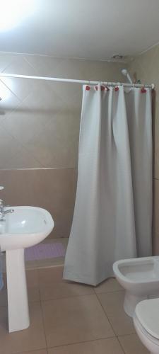 baño con cortina de ducha blanca y lavamanos en Castor Fueguino: departamento cálido, céntrico y equipado - Wi Fi en Ushuaia