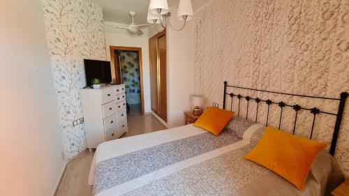 a bedroom with a bed with two orange pillows at Tirreno Vacances in San Juan de los Terreros