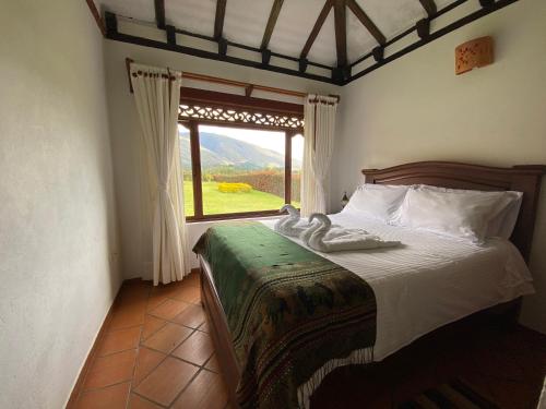 ein Schlafzimmer mit einem Bett und einem großen Fenster in der Unterkunft Cabañas Sol y Luna in Villa de Leyva