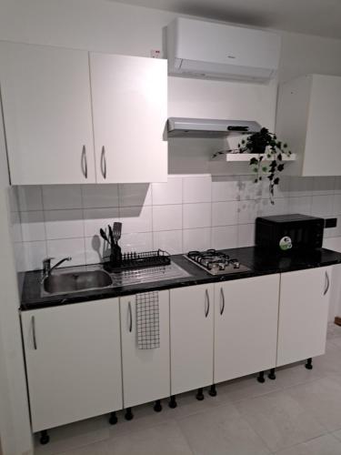 a kitchen with white cabinets and a black counter top at Holiopolis in St Paul's Bay