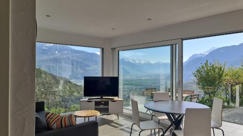 a living room with a television and a table and chairs at Bella Flocon appartements min 2 Nights Special weekly and monthly prices in Savièse
