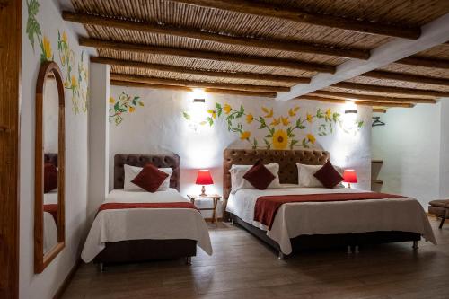 a bedroom with two beds and a wooden ceiling at Hotel Spa Casa de Adobe Villa de Leyva in Villa de Leyva