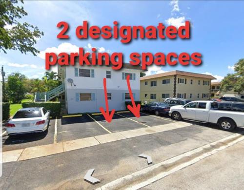 budynek z dwoma wyznaczonymi miejscami parkingowymi na parkingu w obiekcie Glam 2 Bedroom Apartment Close to NSU in Cooper City w mieście Cooper City