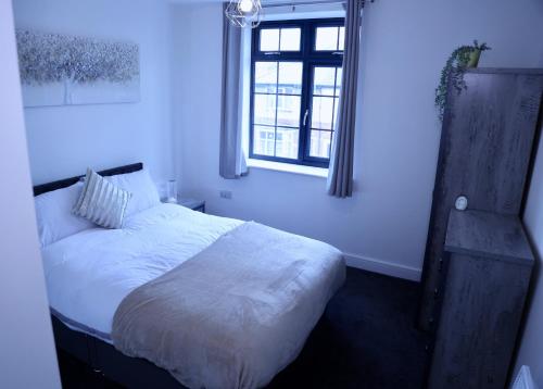 ein Schlafzimmer mit einem weißen Bett und einem Fenster in der Unterkunft Nottingham Brand New 1BR Apt w/ Full Kitchen City in Nottingham