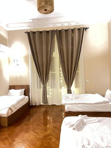 a bedroom with two beds and a window with curtains at Paris east in Cairo