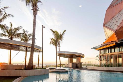 um resort com piscina, palmeiras e um edifício em The Jewel, A designer Condo in the Sky em Gold Coast