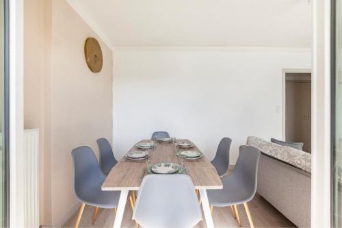 une salle à manger avec une table en bois et des chaises bleues dans l'établissement Appartement logement entiers, à Rodez