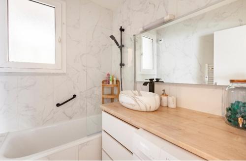 W łazience znajduje się umywalka, wanna i lustro. w obiekcie Appartement logement entiers w mieście Rodez