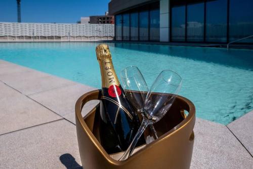 eine Flasche Wein und Gläser in einem Behälter neben einem Pool in der Unterkunft Luxury apartment - Jacuzzi, pool & private terrace in St Julian's