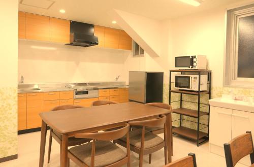 a kitchen with a wooden table and a microwave at Yuyukan in Chitose