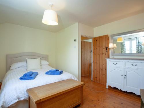 a bedroom with a bed with two blue towels on it at Meadow Pit Cottage in Topsham