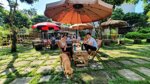 a group of people sitting at a table with a dog at Ninh Binh Bamboo Farmstay in Ninh Binh