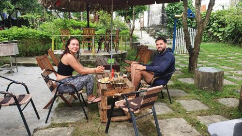 een man en een vrouw zitten aan een tafel onder een parasol bij Ninh Binh Bamboo Farmstay in Ninh Binh