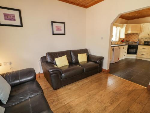 a living room with a leather couch and a kitchen at Creeslough View in Creeslough