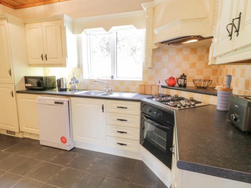 a kitchen with white cabinets and a stove top oven at Creeslough View in Creeslough