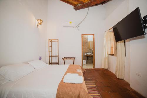 a bedroom with a bed and a flat screen tv at Hotel Archangelus in Mompós