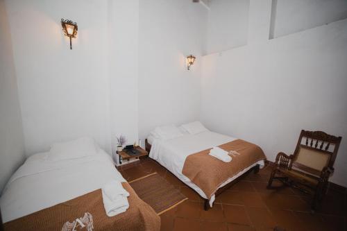 a bedroom with two beds and a chair at Hotel Archangelus in Mompós