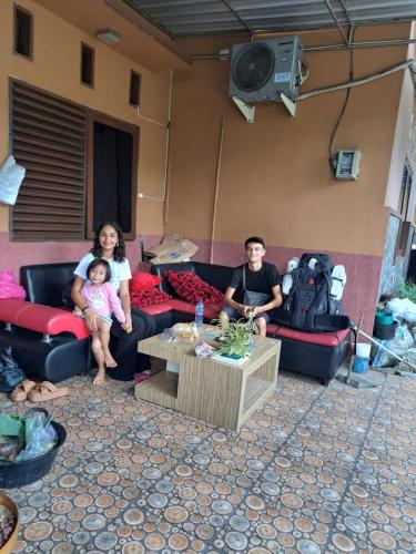 a man and a woman and a baby sitting on couches at Mocca Guest House in Banyuwangi