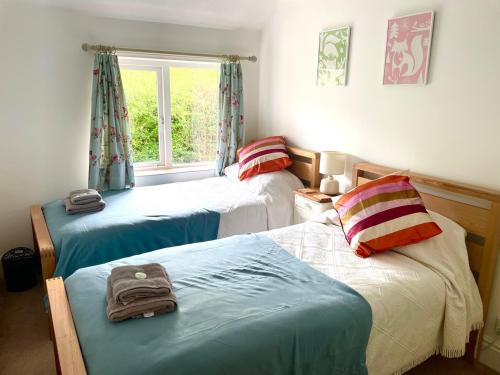 a bedroom with two beds and a window at 2 Smugglers Close in Branscombe
