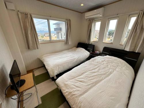 two beds in a small room with windows at SHIRAHAMA condominium D-157 in Kanayama