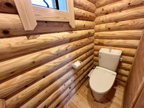 a log cabin bathroom with a toilet and a window at SHIRAHAMA condominium K-32 in Kanayama