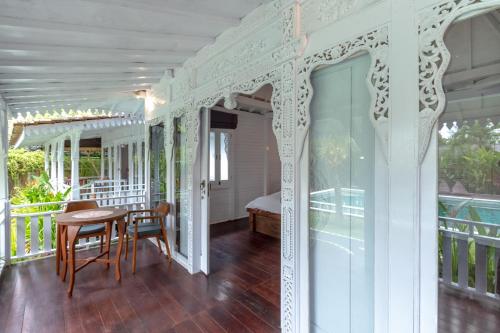 Ein weißes Zimmer mit einem Tisch und einem Bett auf einer Veranda. in der Unterkunft Elysium Bingin in Uluwatu