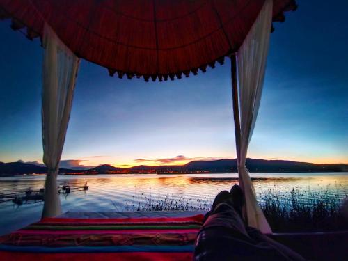 a person laying on a bed in front of a body of water at Titicaca Origins Perú in Puno