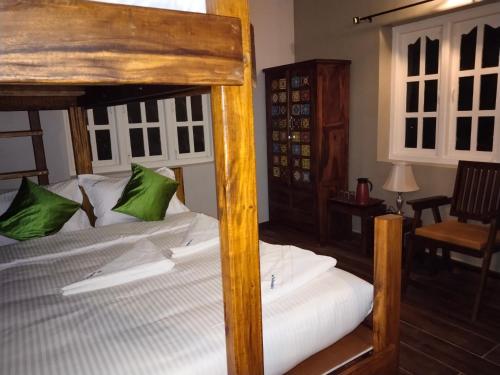 - une chambre avec un grand lit en bois et des oreillers verts dans l'établissement INN THE MOUNTAIN'S, à Kodaikānāl