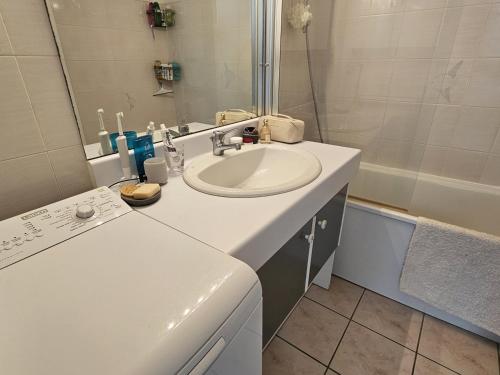 La salle de bains blanche est pourvue d'un lavabo et d'une baignoire. dans l'établissement Superbe duplex à 200m de la plage avec terrasse et garage - FR-1-71-99, à Saint-Georges-de-Didonne