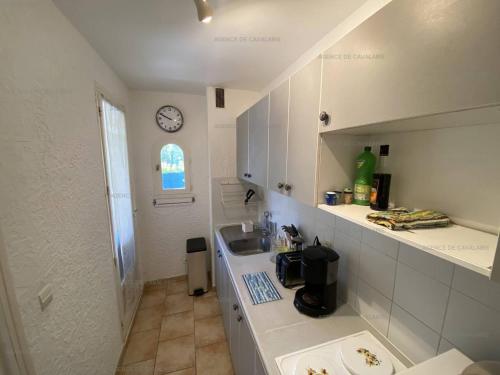 - une petite cuisine blanche avec un évier et une horloge dans l'établissement Appartement T3 - Proche commerces, port et plages - Résidence sécurisée avec parking - FR-1-100-304, à Cavalaire-sur-Mer