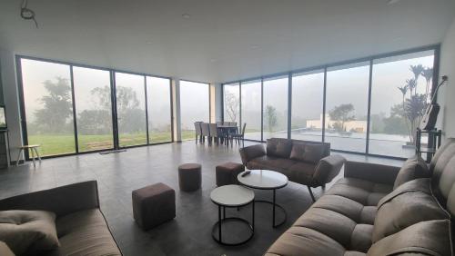 a living room with a couch and tables and large windows at Du Lịch Lâm Hà - Hồ Gia Trang Villas in Lam Ha